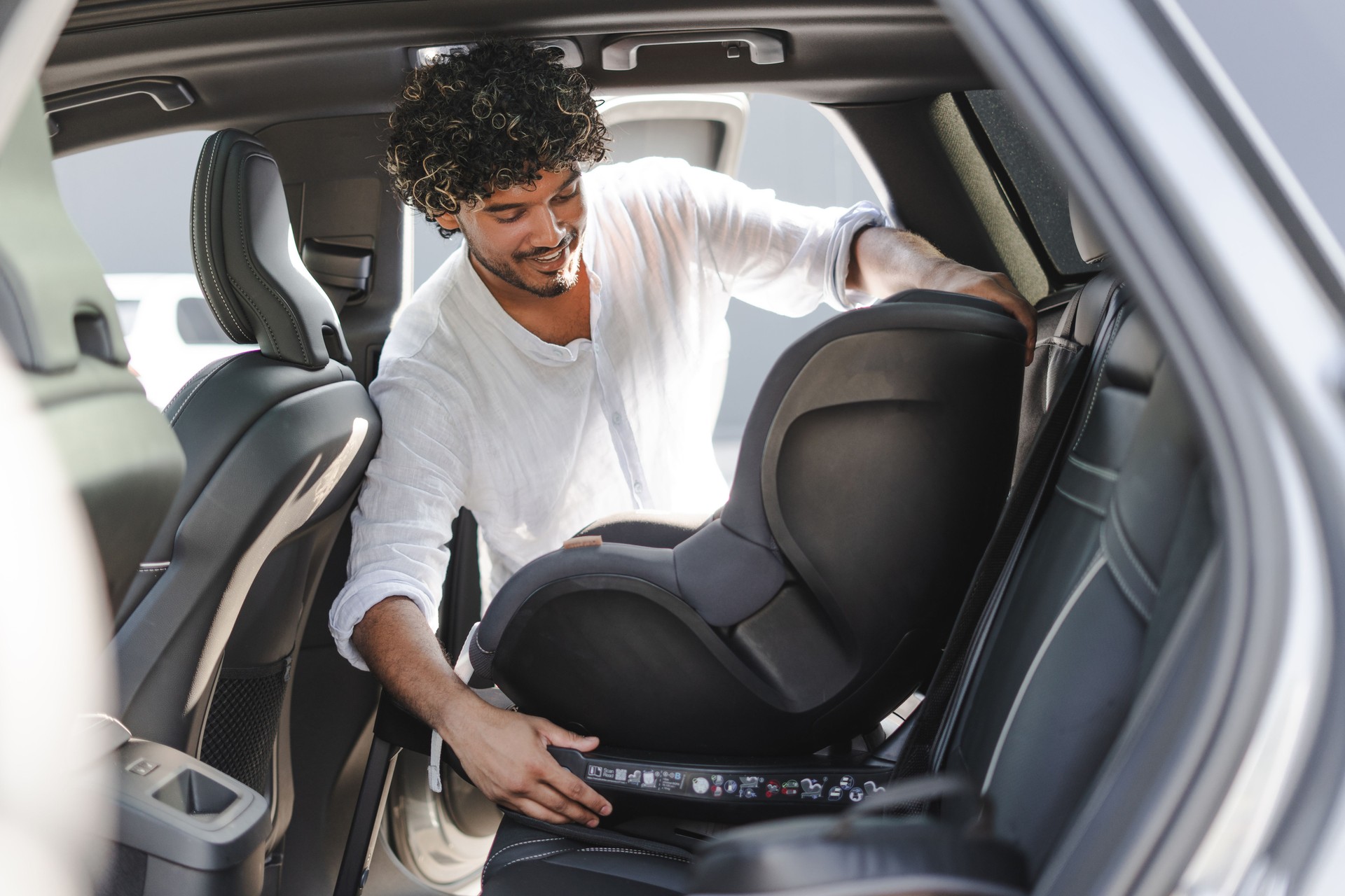 Father installing baby car seat in modern vehicle